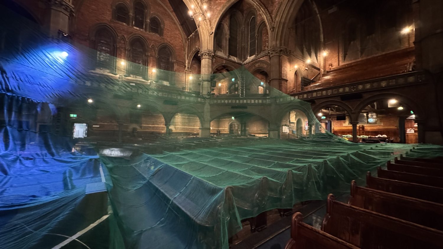 Debris netting being deployed across the chapel interior during the overnight installation