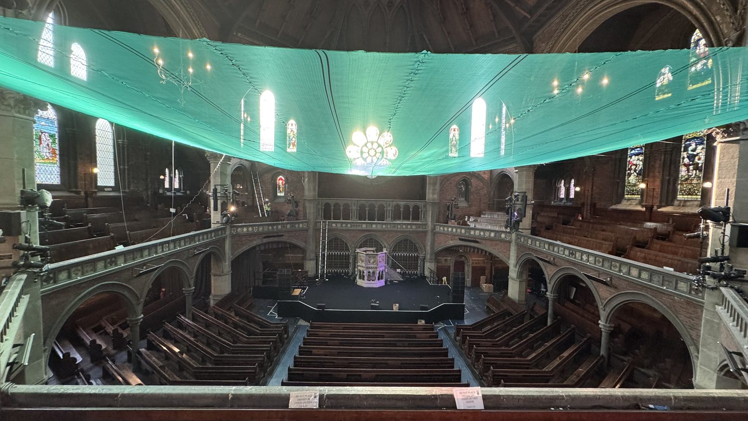 Temporary debris netting installed across the full width of the main chapel space beneath the roof
