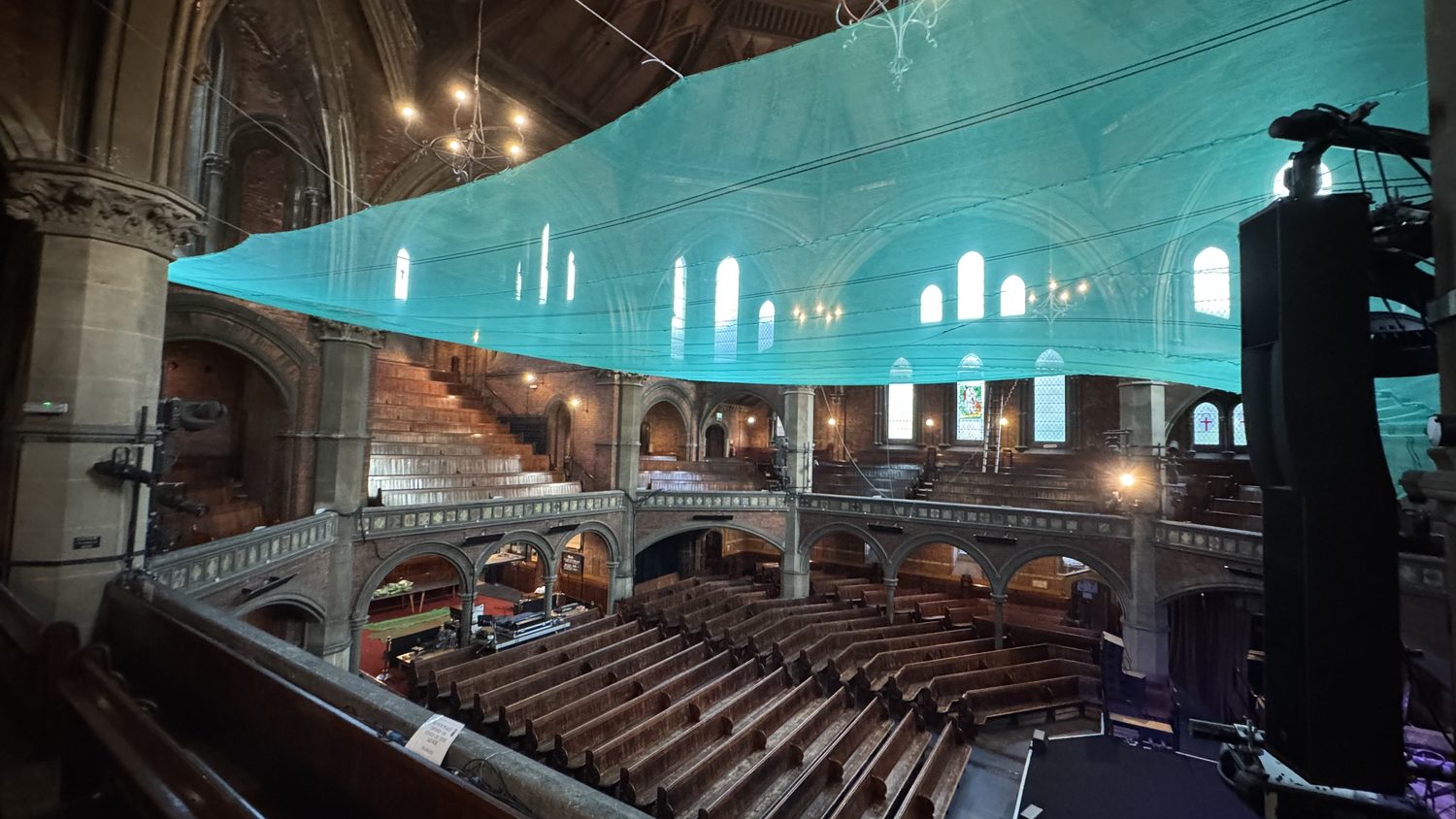 Edge of the installed debris netting running to the wall of the chapel, showing the line and tension